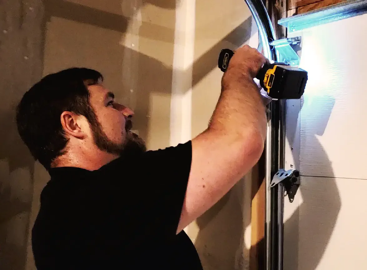 Peter drilling the top panel bracket of a new garage door by torchlight.